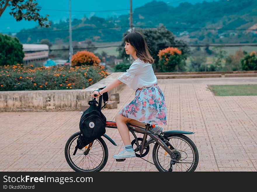 Woman Riding Bicycle Overlooking Orange Flowers and Hills