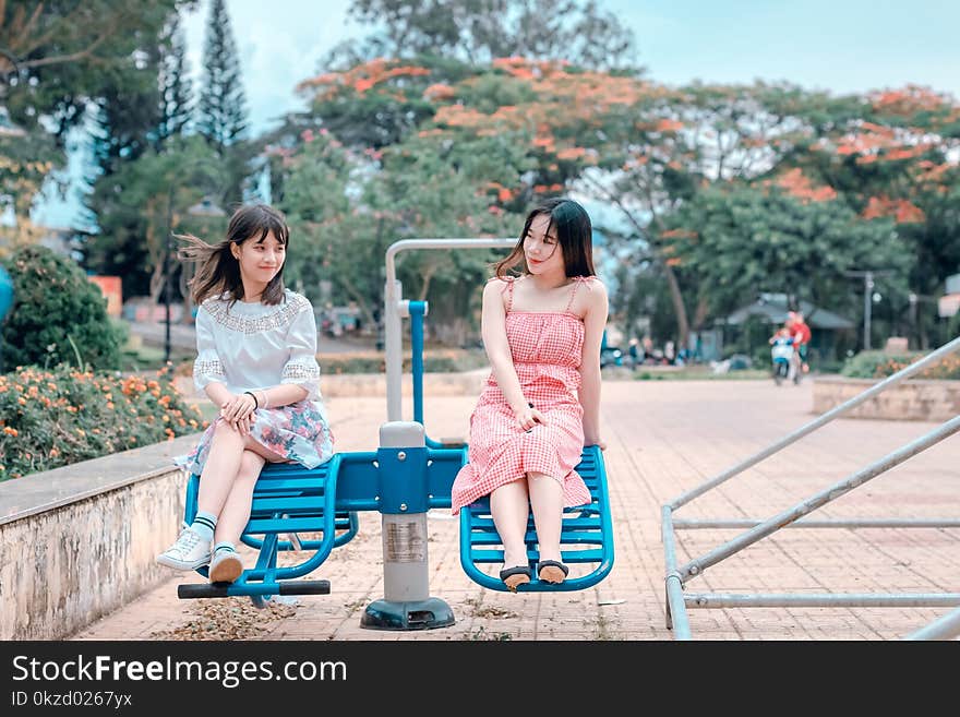 Two Women Sitting in Blue Park Ride