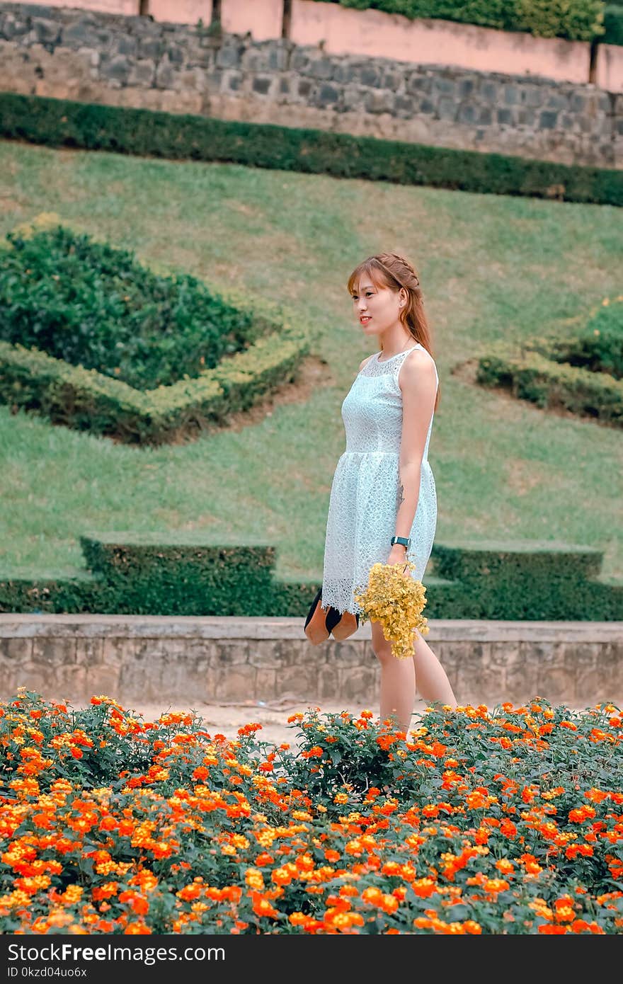 Women&#x27;s White Sleeveless Dress Holding Yellow Flowers