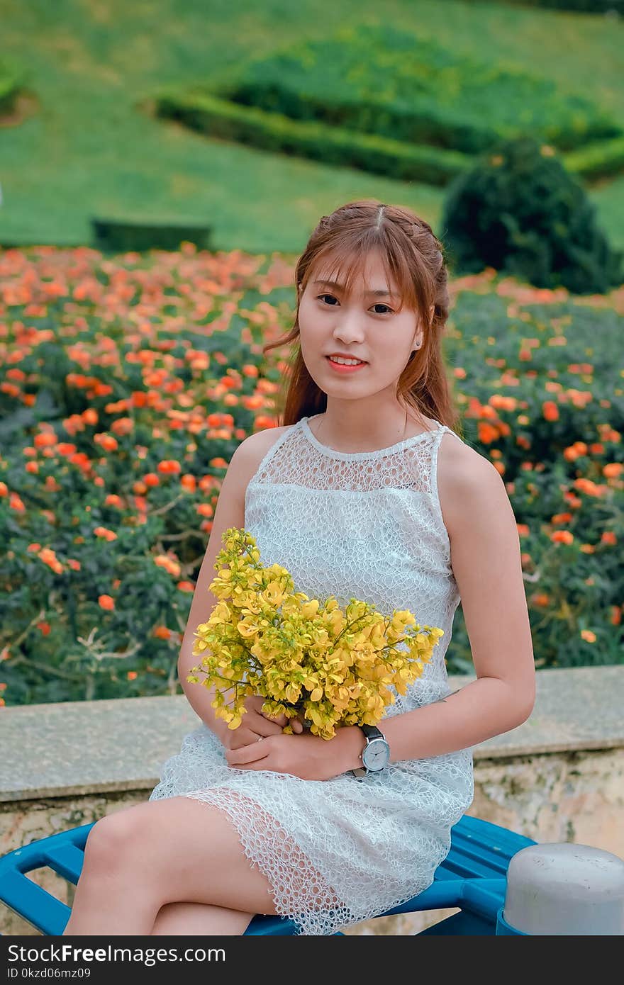 Focus Photo of Woman Wearing Dress While Holding Bouquet of Yellow Flowers