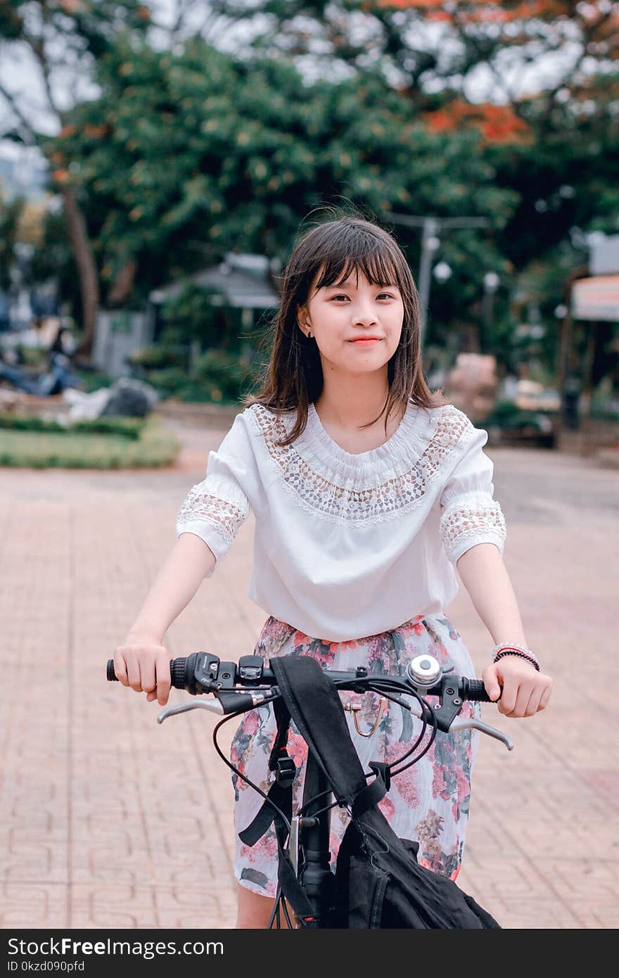 Woman Wearing White Blouse and Multicolored Floral Skirt Riding Bike