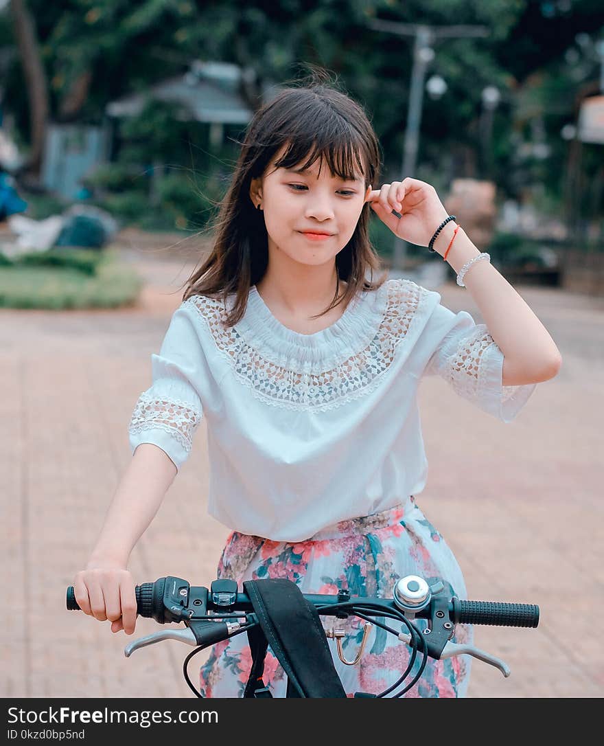 Woman Wearing White Blouse and Multicolored Floral Skirt Riding Bike