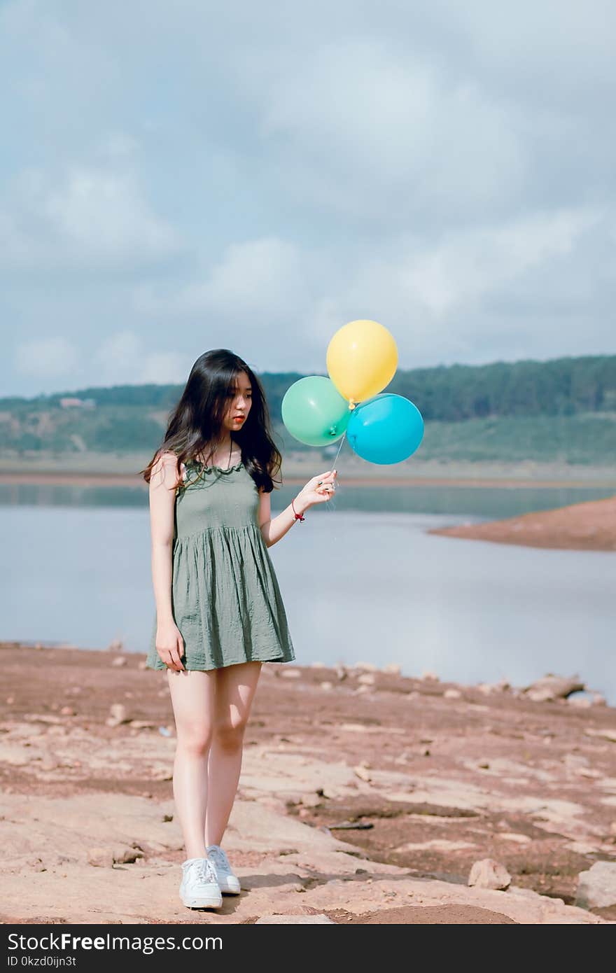 Woman in Green Sleeveless Dress Holding Balloons