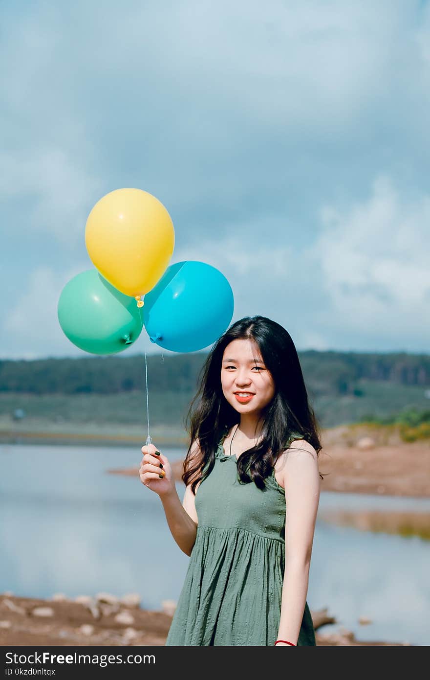 Woman Wearing Green Dress Holding Balloons Near River