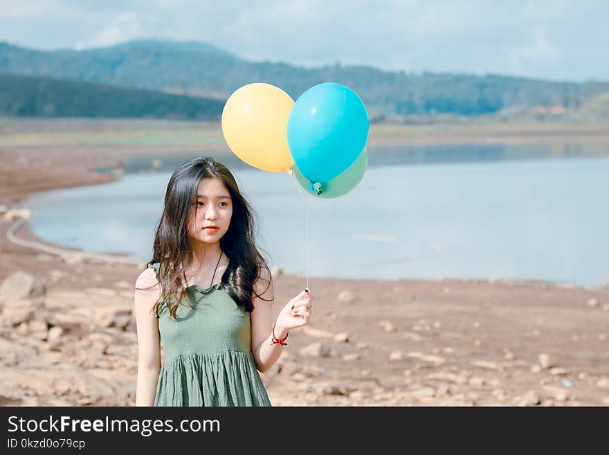 Shallow Focus Photography of Woman Holding Three Assorted-color Balloons