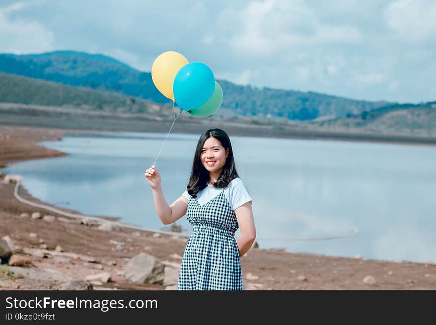 Woman Near Seashore Holding Balloons