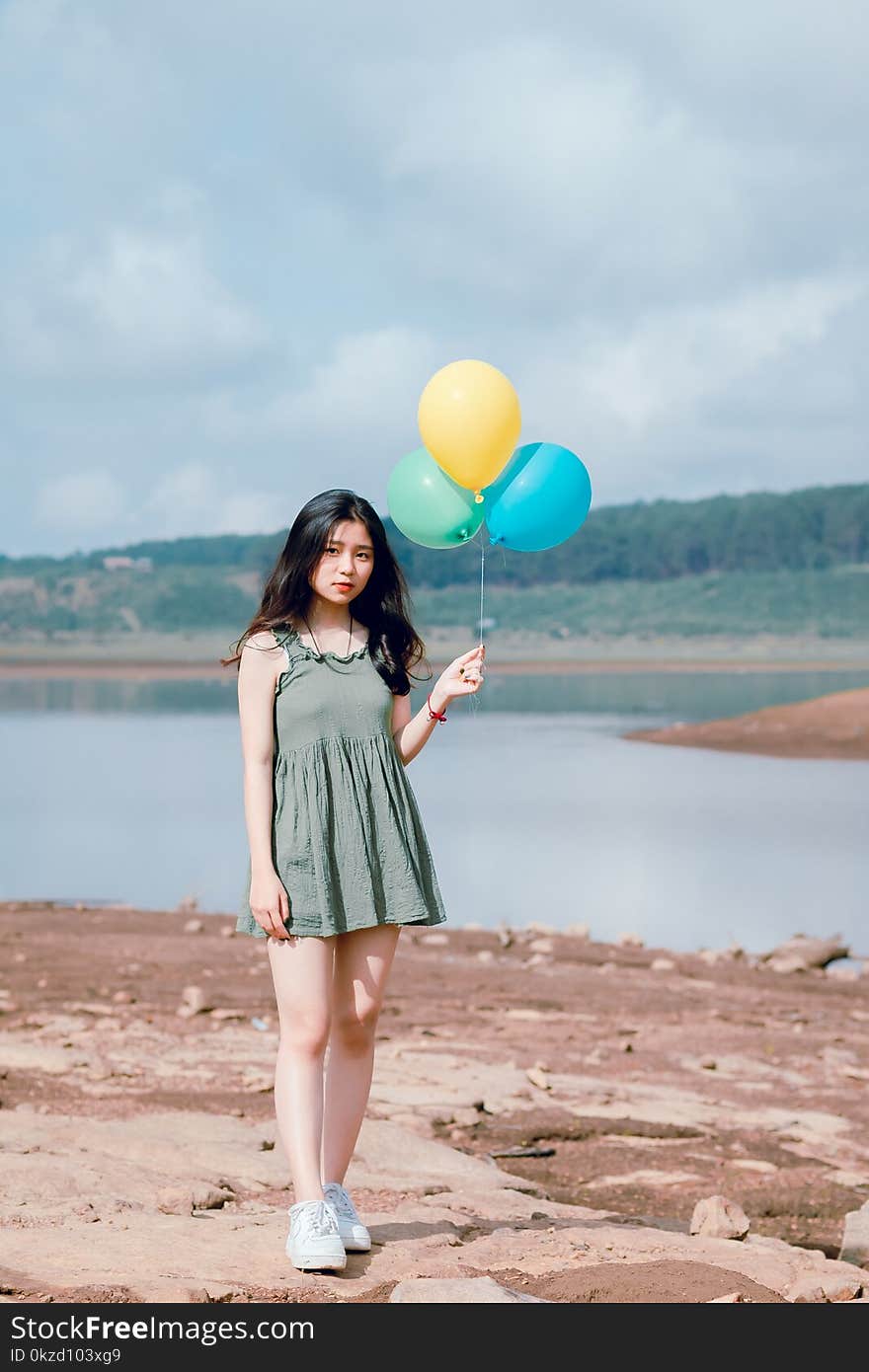 Woman&#x27;s in Green Sleeveless Dress Holding 3 Balloons