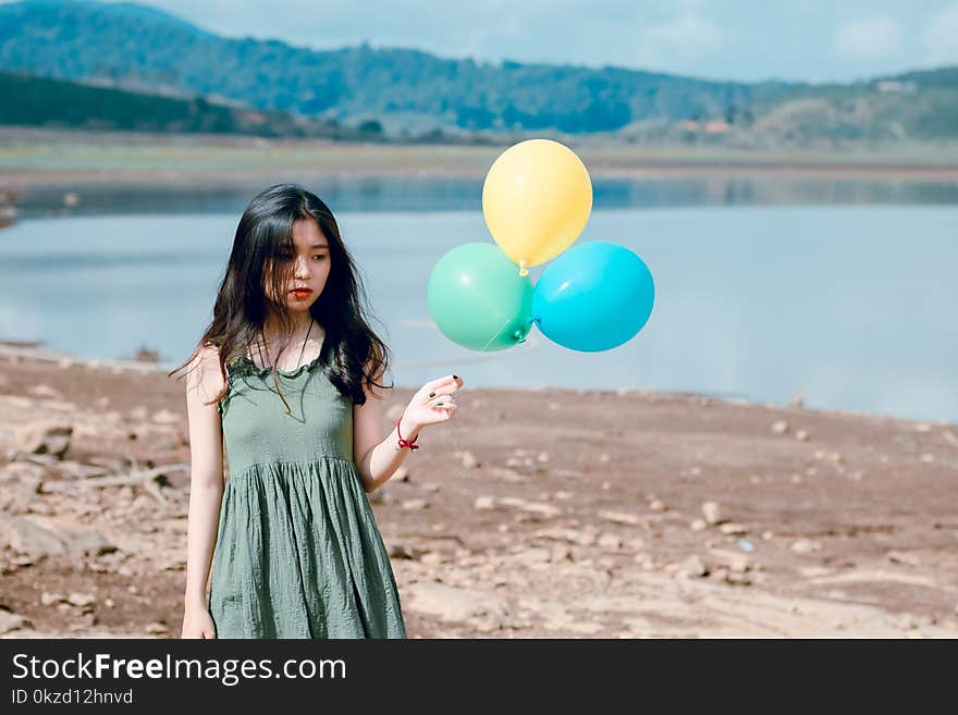 Woman in Green Sleeveless Dress Holding Three Balloons