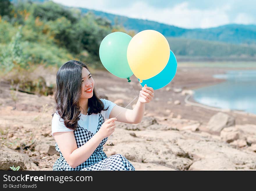 Woman in White and Black Dress Holding Three Balloons