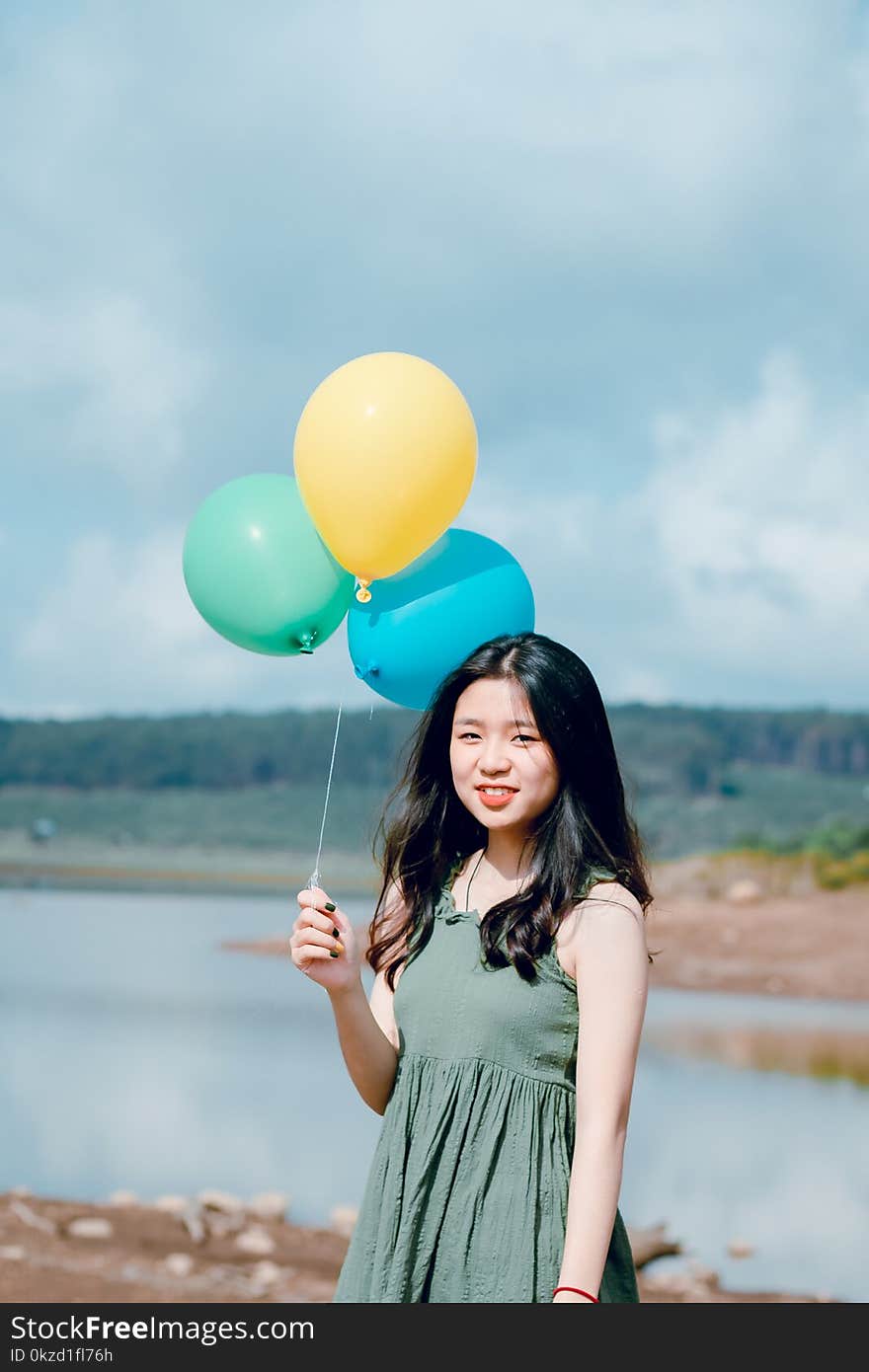 Woman in Green Sleeveless Top Holding Balloons