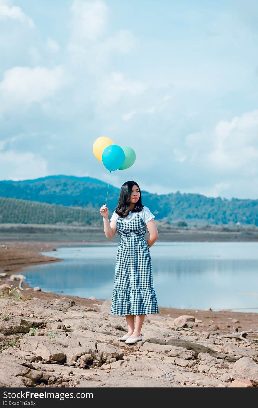 Woman Holding Balloons Near River