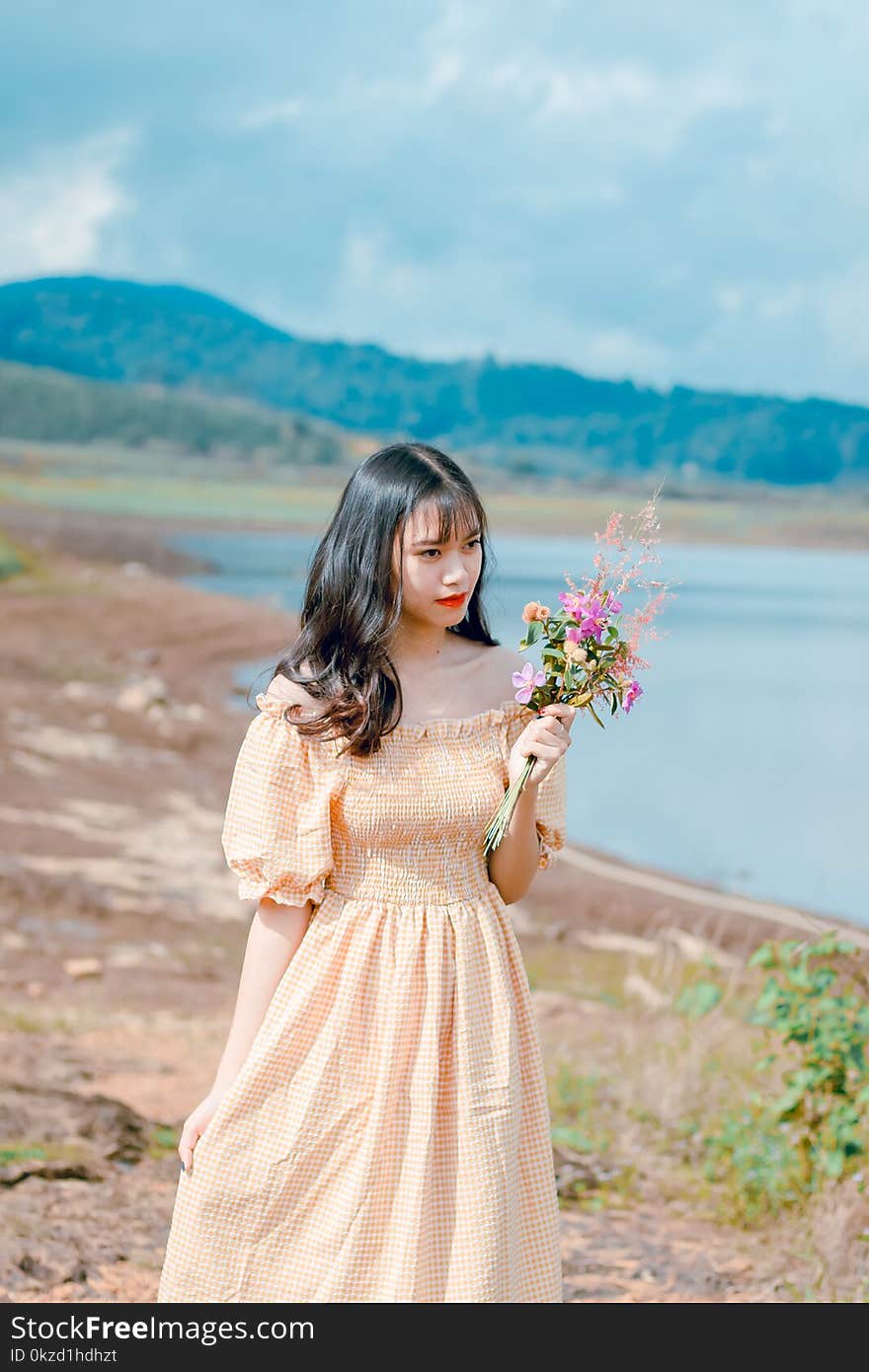 Shallow Focus Photography of Woman in Beige Off-shoulder Dress Holding Bouquet of Flowers