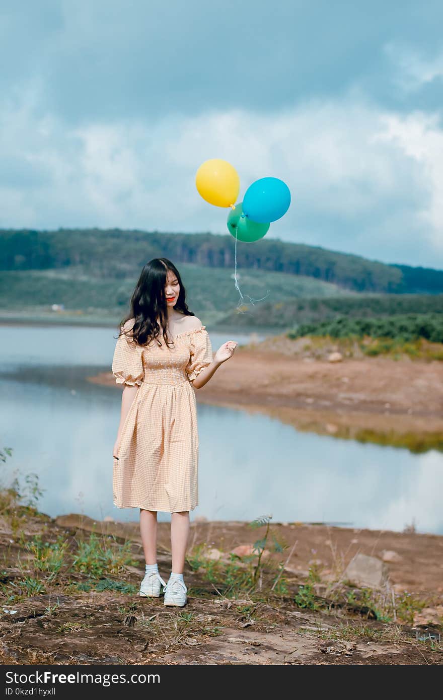 Woman in Beige Off-shoulder Dress Holding Balloons