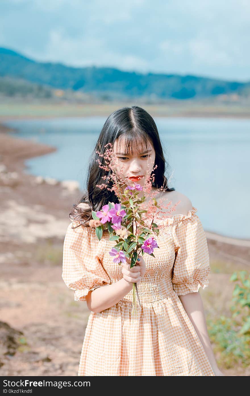 Woman in Orange and White Gingham Check Off-shoulder Dress Holding Pink Petaled Flowers