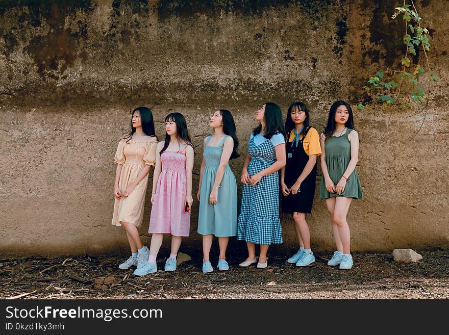 Photography of Six Girl Standing Beside Wall