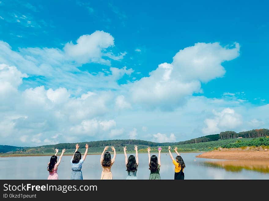 Group of Women Wearing Dress Raising Up Their Hands on Air Under Cloudy Sky