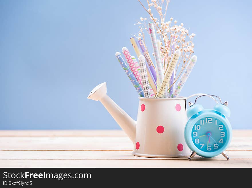 Pencil and pen in watering can have clock on wood vintage with office concept