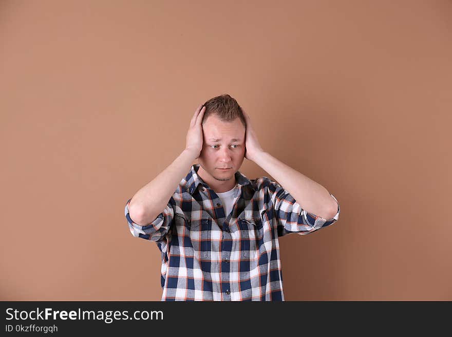 Handsome man suffering from headache on color background