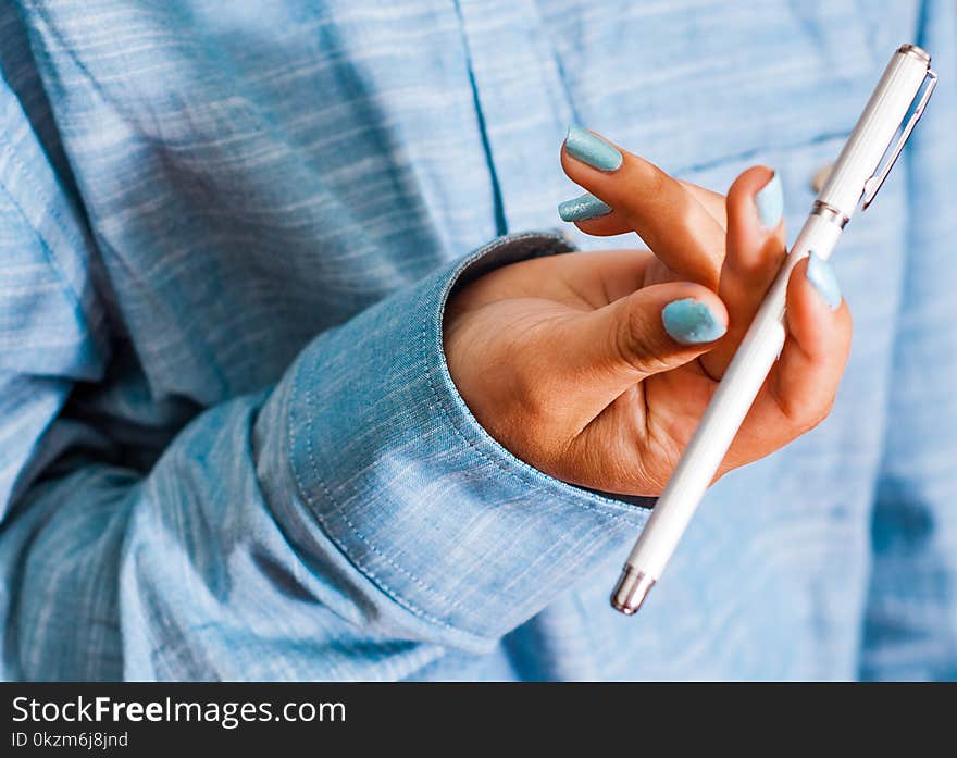 Cropped image of woman in blue shirt Hold pen in your hand. pen spinning