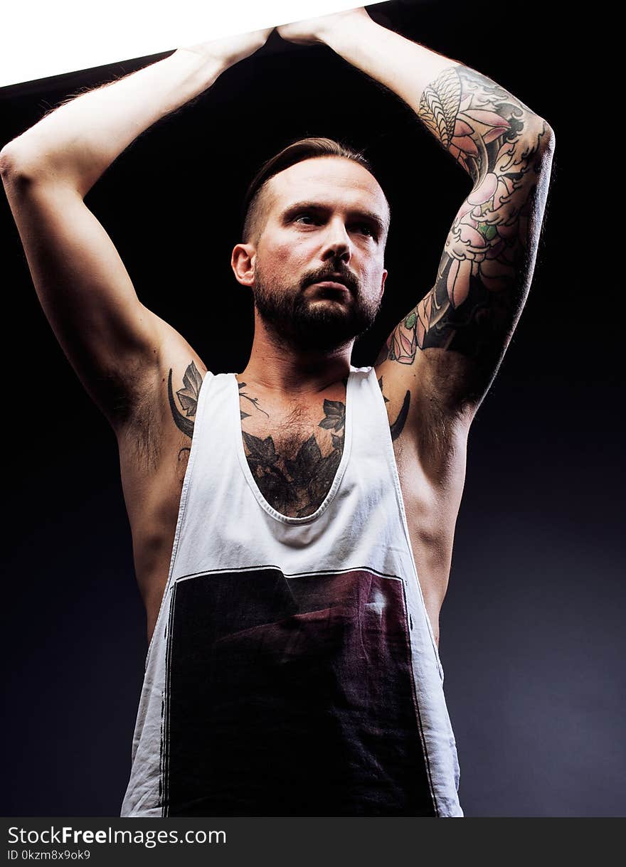 A man with tattooes on his arms. Silhouette of muscular body. caucasian brutal hipster guy with modern haircut, looking like criminal close up