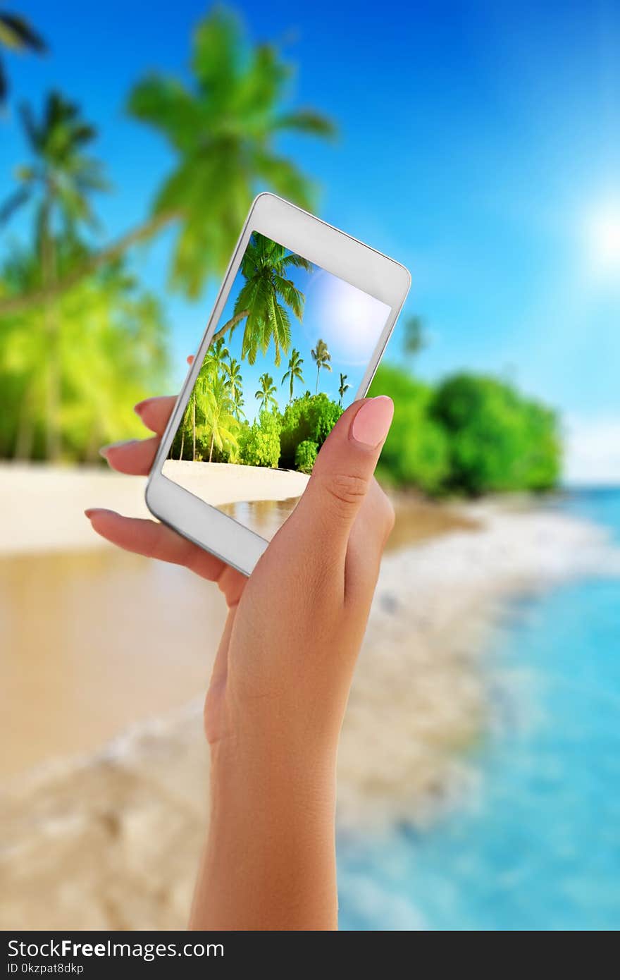 Close up hand holding smartphone on summer beach. technology, travel, tourism, communication and people concept.