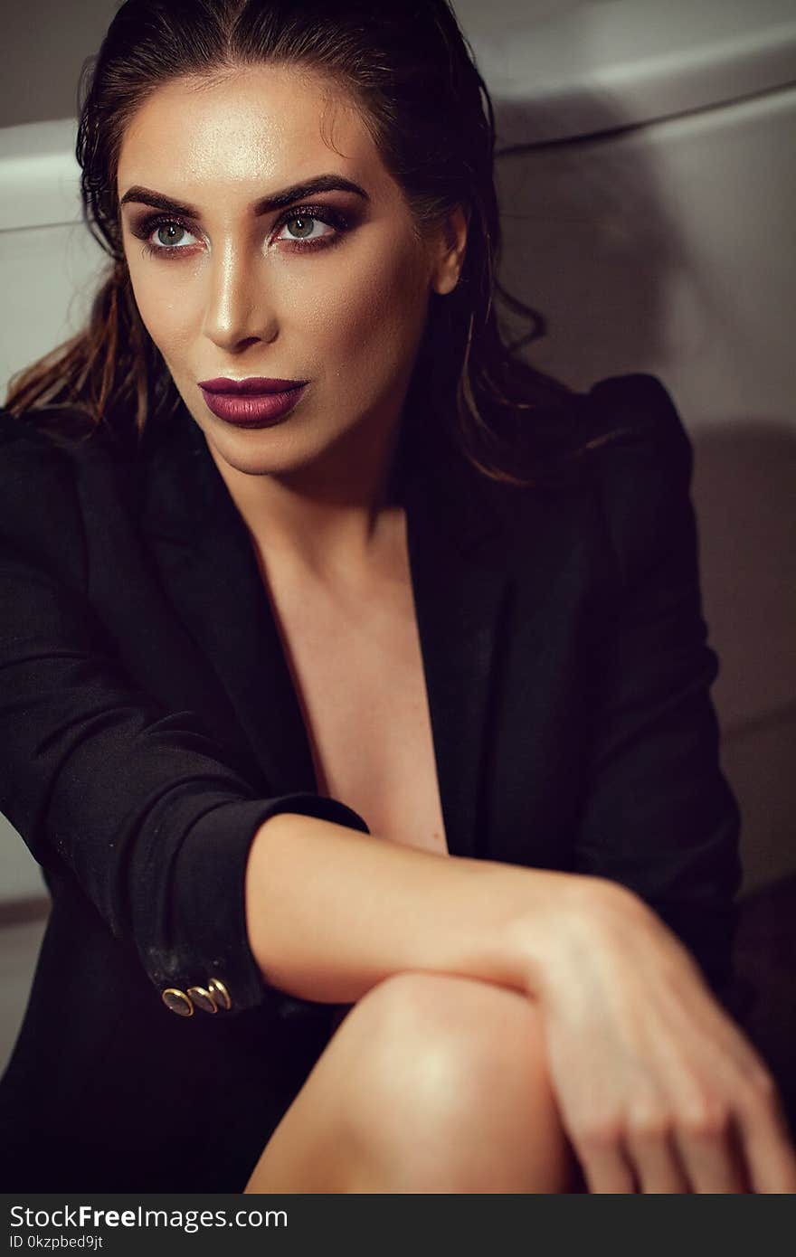 brunette woman posing in armchair in fashionable black dress.