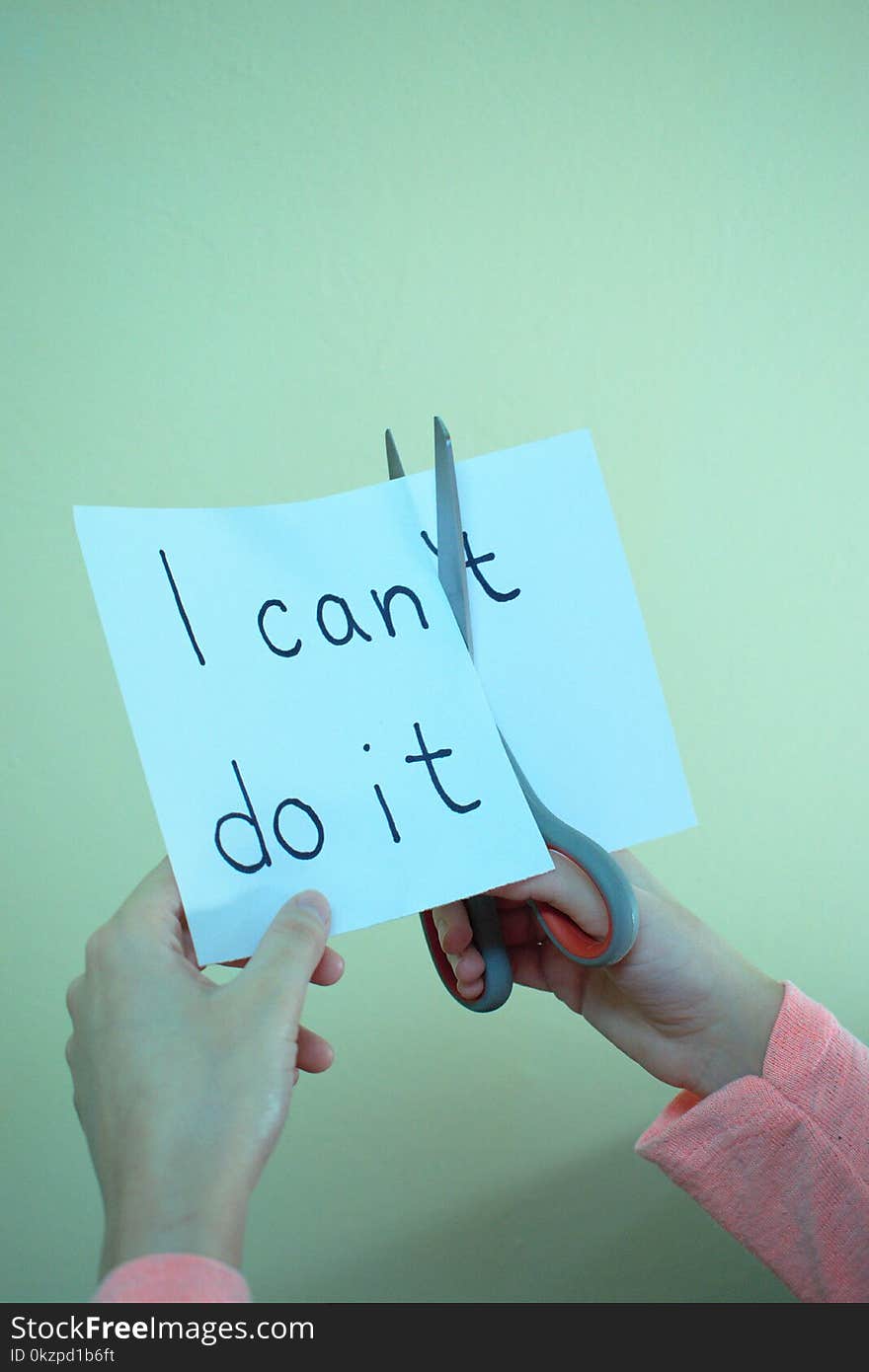 Closeup of hands cutting a piece of paper with `I can`t do it` written. Closeup of hands cutting a piece of paper with `I can`t do it` written