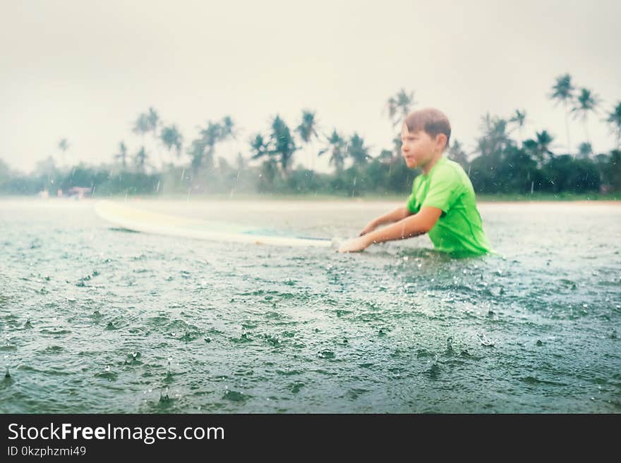 Boy first step surfer learning to surf under the rain