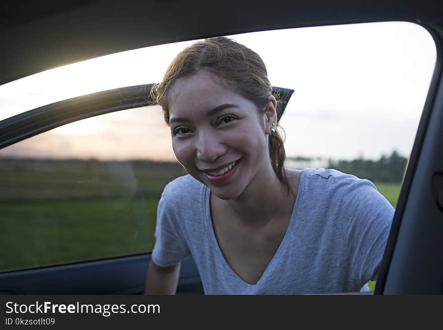 Close up portrait of smiling young lady entering a car. Back lit by a sunset. Close up portrait of smiling young lady entering a car. Back lit by a sunset.