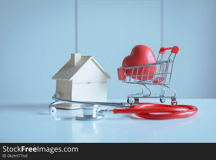 Mini shopping cart,Red heart with home model piggy bank on table,Health and money saving concept