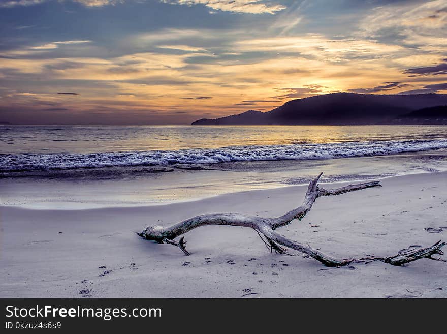 Body of Water Near Mountain Under Gray Sky at Golden Hour