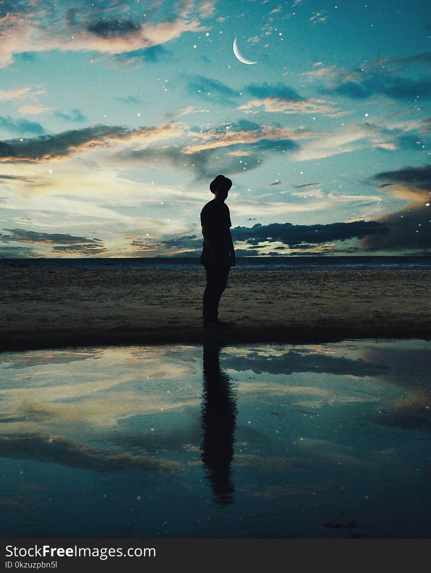 Silhouette of Man Standing Near Body of Water