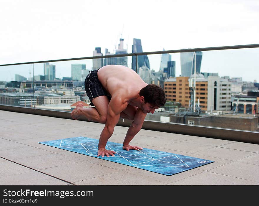 Man Doing Yoga on Mat Near Glass Balcony Fence