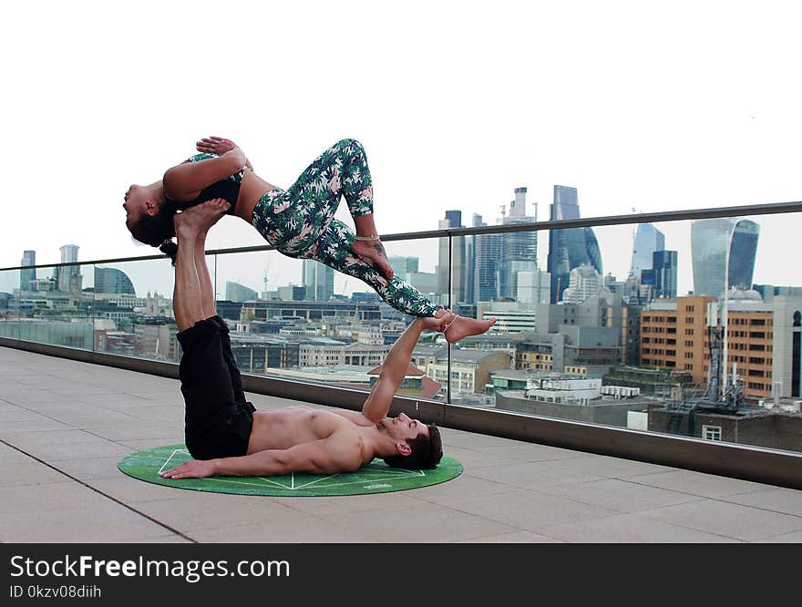 Man Lying Down on Mat While Lifting Woman