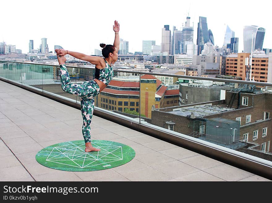 Woman on Round Green Yoga Mat Position in Right Leg High and Left Hand Upright Posiiton