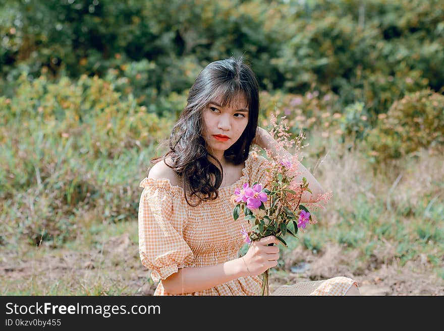 Shallow Focus Photography of Woman in Beige Off-shoulder Dress Holding Bouquet of Flowers