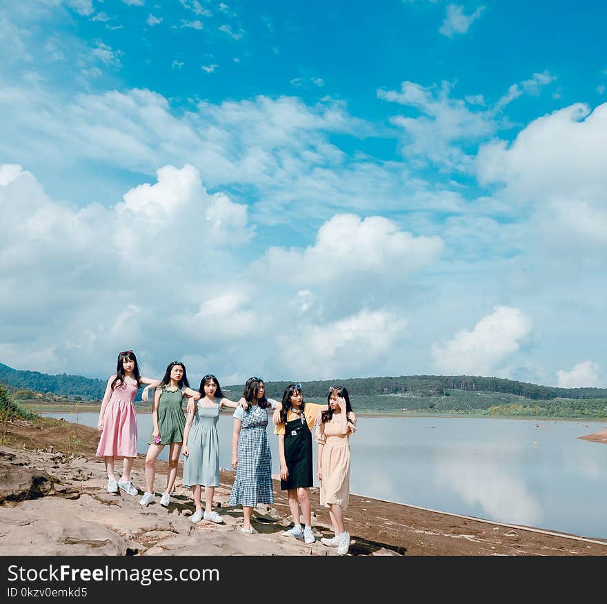 Group of Women Wearing Dress Standing Near Body Of Water