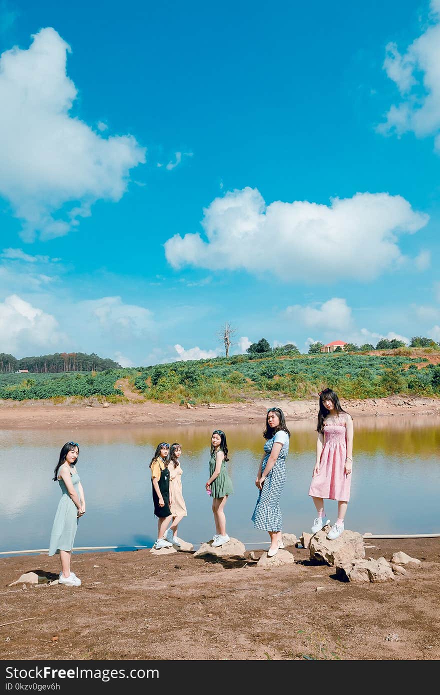 Group Of Women Standing Besides Body Of Water