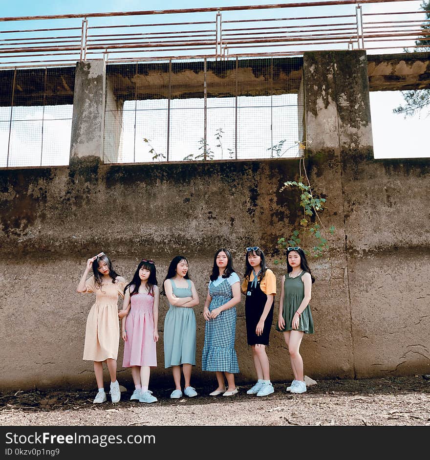 Group of Women Standing Near Brown Wall