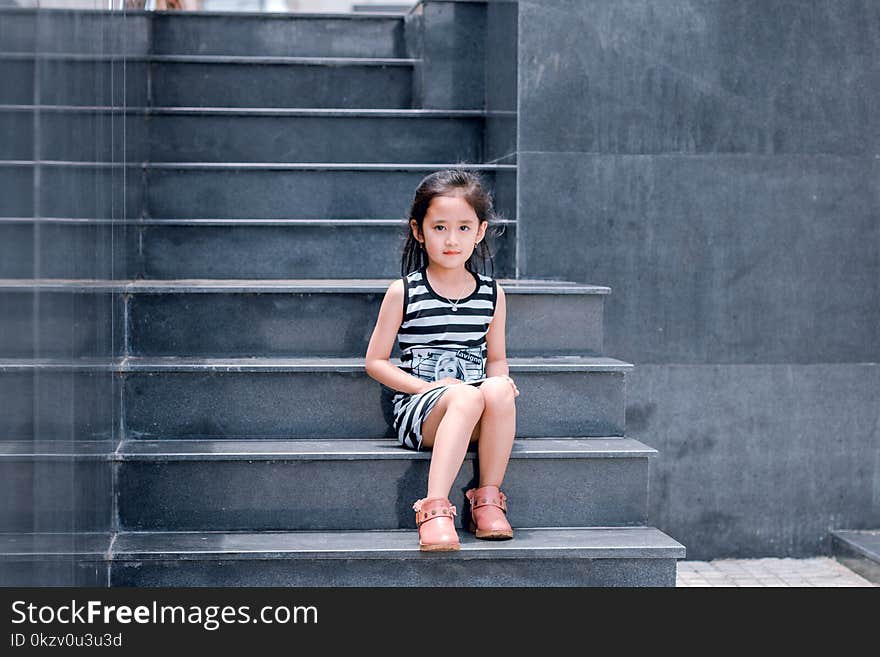 Girl Wearing Black and White Striped Dress Sitting on Stair