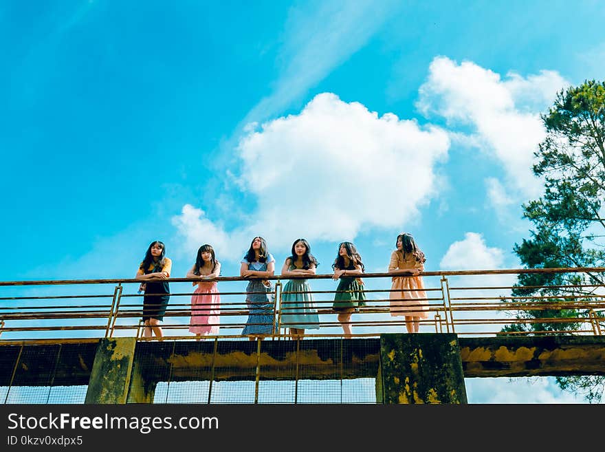 Six Women Wearing Dress Leaning on Bridge Rail