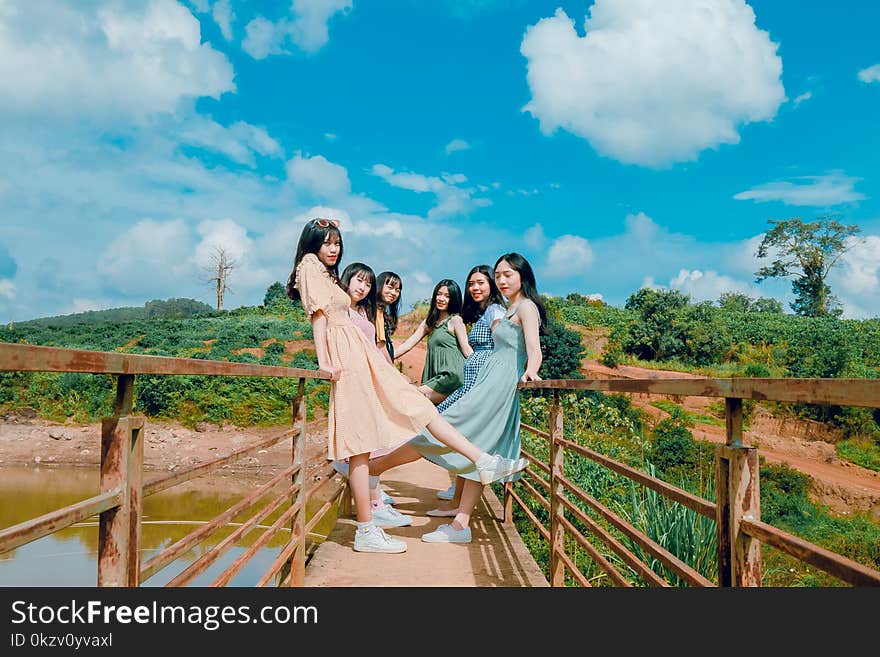 Group of Women Standing on Brown Bridge