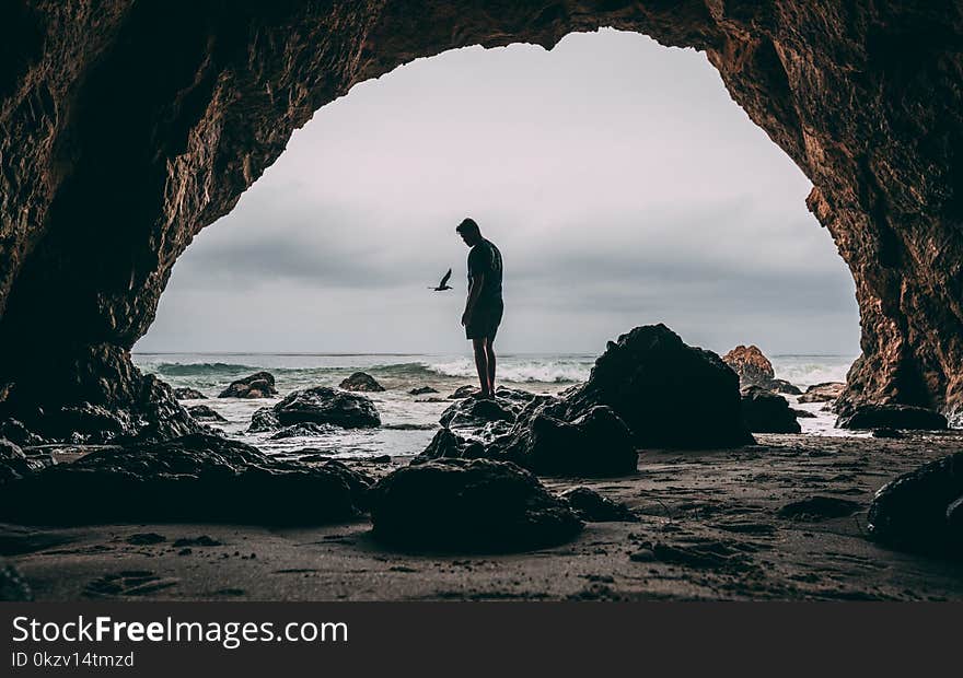 Photo of Man Standing on Rock Near Seashore