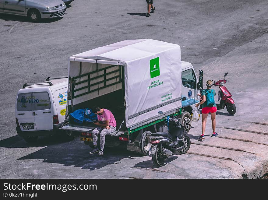 Man in Pink Shirt Sitting at the Back of White Truck