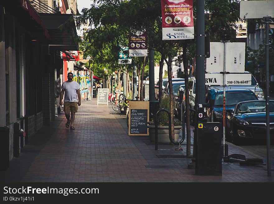 Man Wearing White Crew-neck T-shirt Walking On Sidewalk