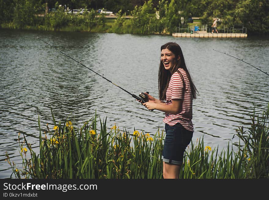 Woman in Red Striped Shirt and Blue Denim Shorts Holding Fishing Rod