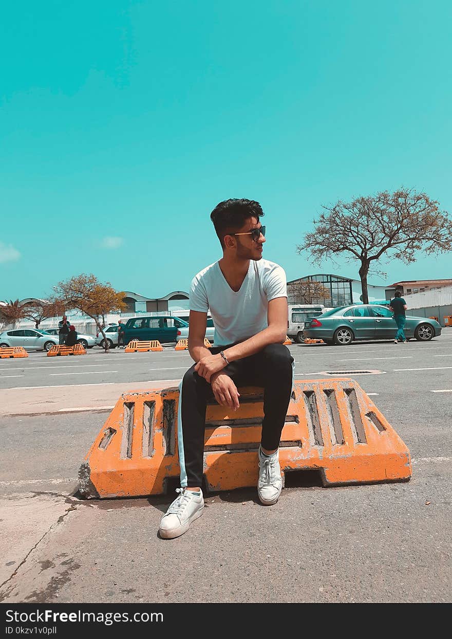 Man In White Shirt Sitting On Orange Concrete