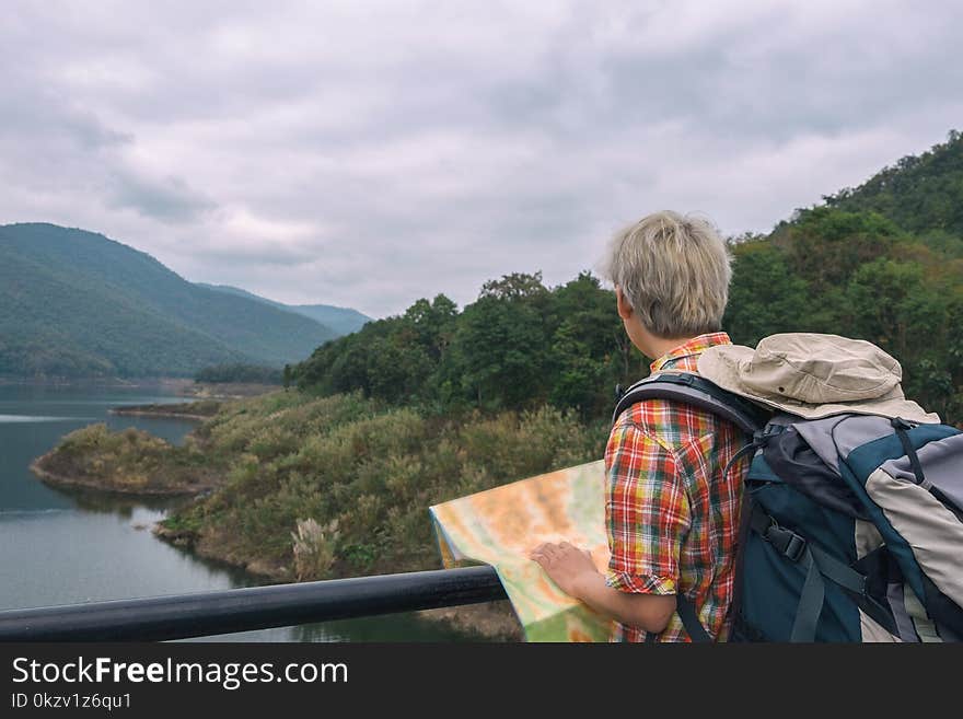 Man in Red, Yellow, Blue,and White Plaid Collared Top With Blue and Gray Backpack