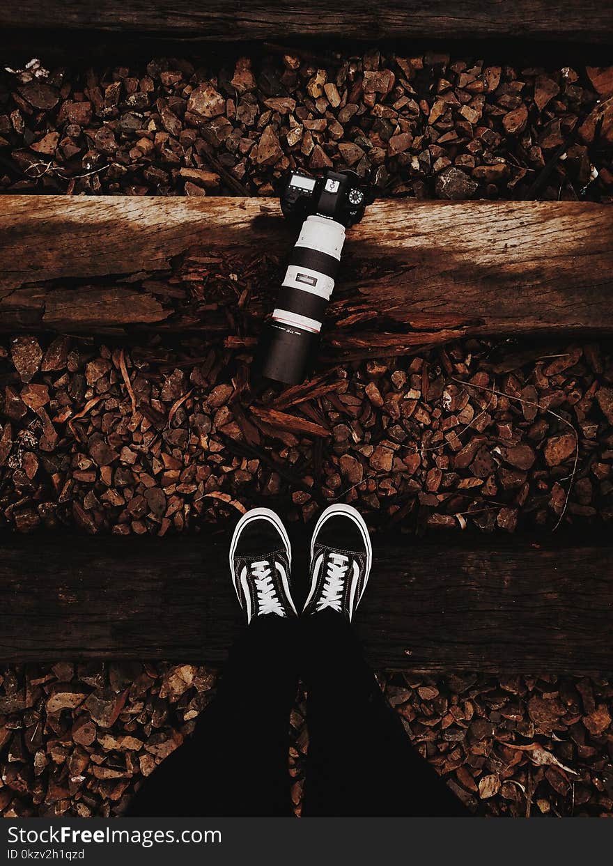 Person Wears Black-and-white Vans Low-top Sneakers Stands In Front of Black Dslr Camera