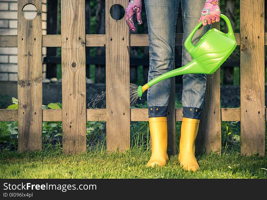 Watering grass in yellow wellies, spring season